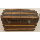 A Victorian dome top, wooden banded travelling trunk on metal casters.
