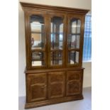 A large mirror backed, solid wood display unit with glass doors and cupboard base.