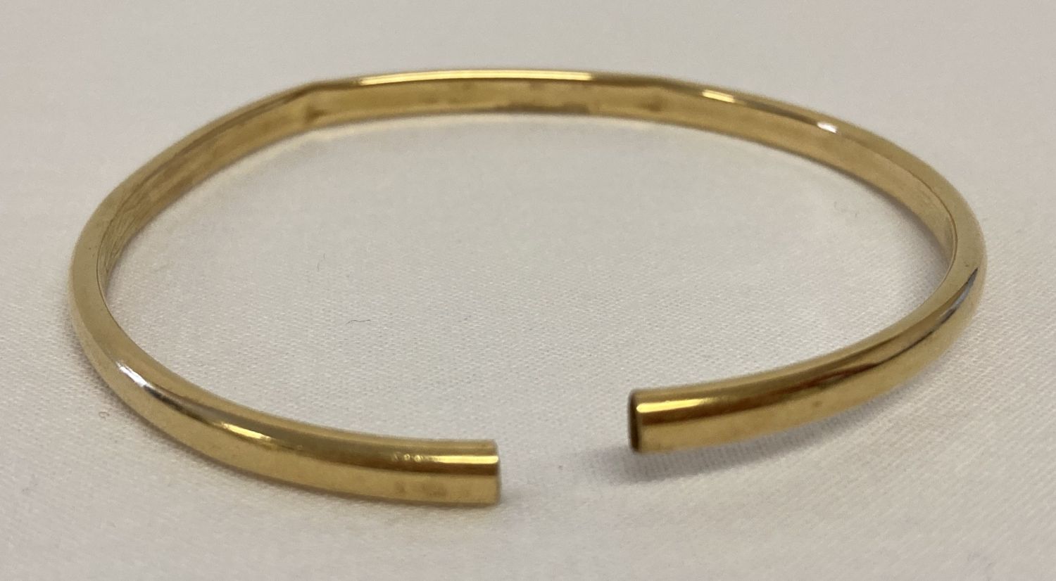 A cut through scrap gold bangle with indistinct marks to outside rim.