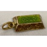 A gold charm/pendant with bale in the shape of a gold bar with green enamel to top. Tests as 9ct.