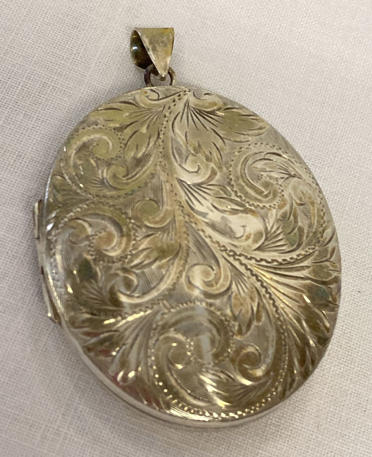 A large vintage silver locket with floral engraved decoration to front.