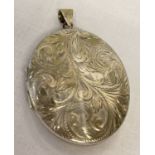 A large vintage silver locket with floral engraved decoration to front.