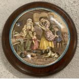 A ceramic pot lid depicting a family reading a letter in a circular wooden frame