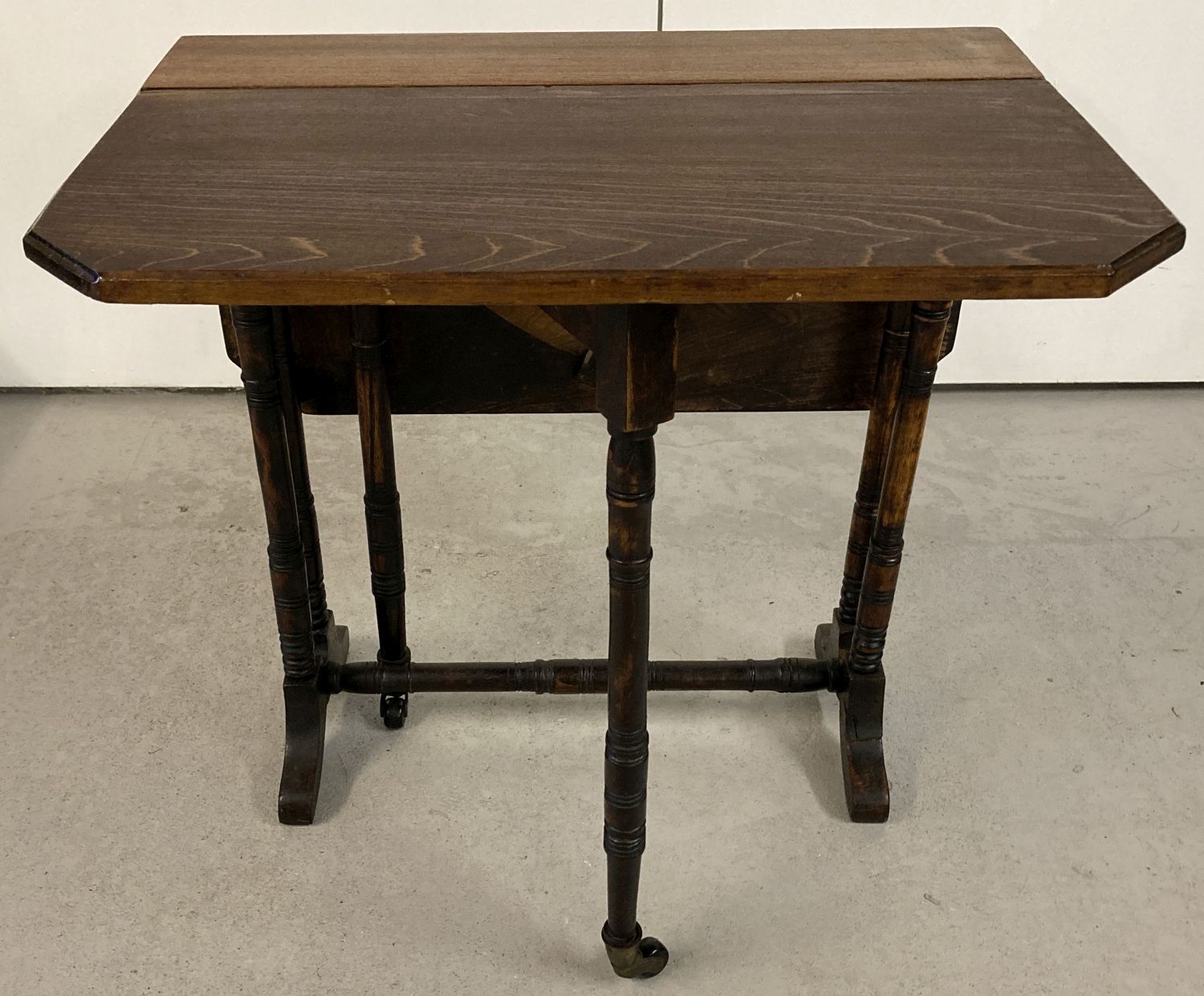 An antique small Sutherland table with turned legs and supports with original ceramic casters.