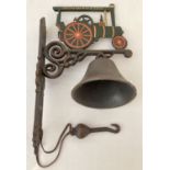 A painted cast metal wall hanging garden bell with Joseph Brewer & sons Traction engine detail.