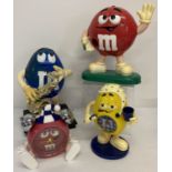 2 large M&M's advertising sweet dispensers, one playing a saxophone.