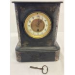 An antique black slate and marble wind up mantle clock, complete with key.