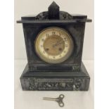 An antique slate and marble chiming mantel clock with gilt detailed face.