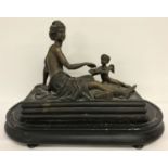A filled bronze of a reclining semi naked classical female figure with cherub offering fruit.