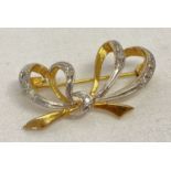 A 9ct white and yellow gold bow design brooch set with 11 small round cut diamonds.