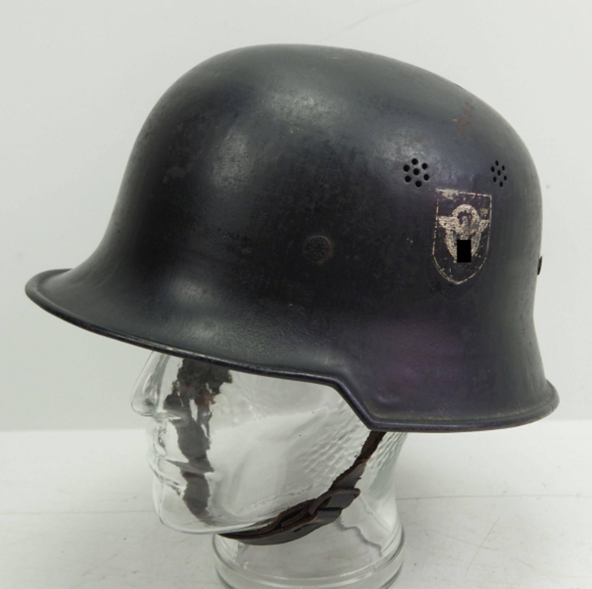 Feuerlöschpolizei: Helm.Schwarz lackierter Helm, das Polizei-Emblem zu ca. 75% erhalten, das
