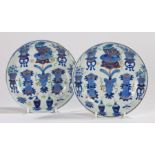 Pair of Chinese porcelain dishes, Qing dynasty, each decorated with blue urns and vases on tables, a