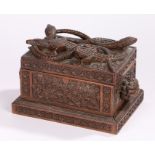 Eastern carved box, with a beast biting a serpent's tail above figural carved handles and foliate
