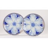 Pair of Japanese porcelain plates, with a central blue flower, one with two enamel butterflies,