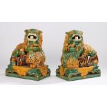 Near pair of Chinese pottery dogs of foo, in mustard yellow and green glaze showing the dogs with