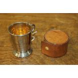 Collapsible plated stirrup/tot cup, with gilt interior and folding handle, housed in a brown leather