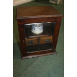 Oak smokers cabinet, the bevelled glazed door opening to reveal two pipe racks, mixing bowl with lid
