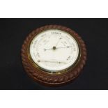 Oak barometer and thermometer. with a carved rope twist edge and white enamel dial