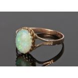 Yellow metal and opal ring, the oval opal set in a pierced crown mount above divided shoulders, ring