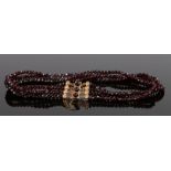 Garnet and gold necklace, with three strands to the necklace ending with the gold clasp, 34cm long