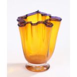 Mike Hunter twists glass vase, with crimped purple rim and amber glass body, on a clear glass