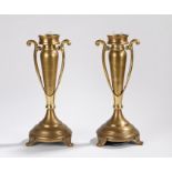 Pair of brass candlesticks, with pierced scroll handles, on splayed bases and reeded scroll feet,