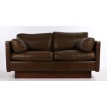 Late 20th Century brown leather two seat settee, raised on a mahogany veneered plinth baseSome