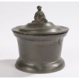 Tin tobacco jar and cover, of cylindrical form, the finial in the form of a seated figure, 10cm