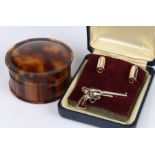 Pair of bullet form cufflinks and a matching tie clip in the form of a revolver, tortoiseshell