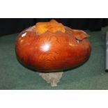 Large carved wooden egg with removable top, raised on a cast metal stand