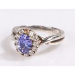 Sterling silver ring, the head set with a central blue stone surrounded by a band of cubic zirconia,