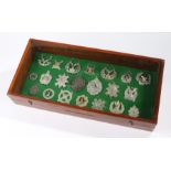Collection of Cap badges displayed in a box frame, the badges are a mix of original and reproduction