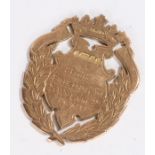 9 carat gold medallion in the form of a shield surrounded by a laurel wreath surmounted by a