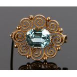 Zircon on gold brooch, with a central blue zircon at and estimated 6.85 carat with a scroll