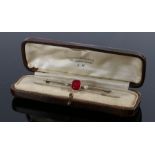 Diamond set bar brooch, with a central red baguette cut stone flanked by diamonds, the brooch