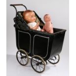 Child's doll pram, in black with rubber to the wheels, together with two dolls, (3)