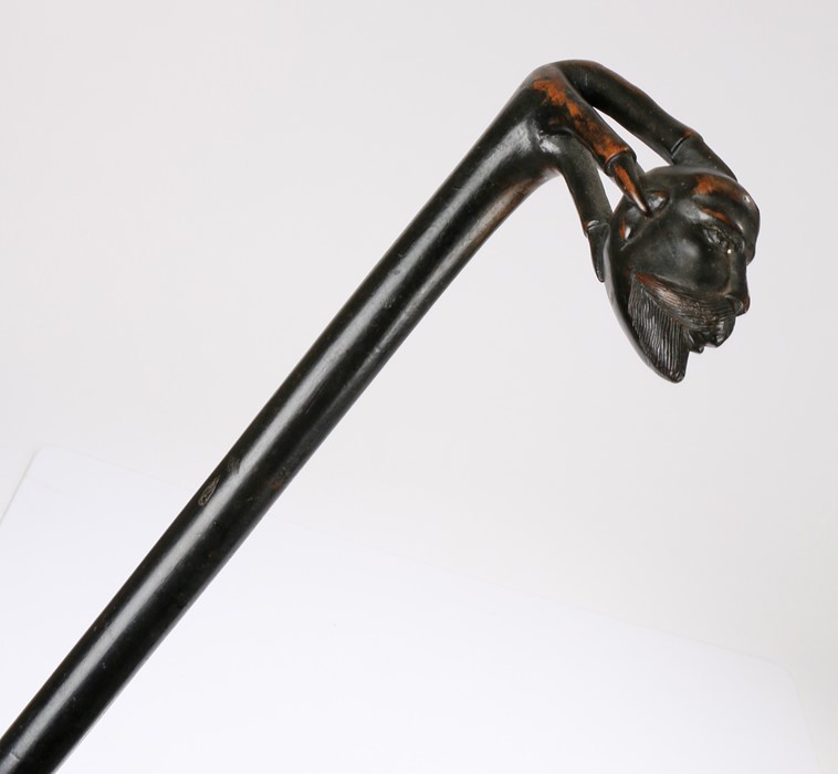 19th Century ebonised walking stick, the handle carved as a claw holding a moustached man's head,