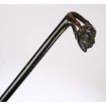 19th Century ebonised walking stick, the handle carved as a claw holding a moustached man's head,