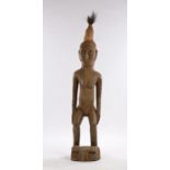 Large West African carved figure, with high hair above the elongated face, hands to the waist and
