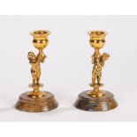 Pair of 19th Century gilt metal candlesticks, each with a boy holding up the socket, both raised