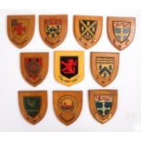 Collection of ten wooden wall shields with emblems of various schools, regiments, colleges etc. to
