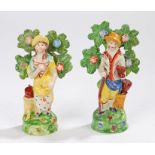 Pair of late 18th Century pearlware figures, of a standing gentleman holding a shovel with a tree