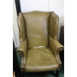 Green leather wing-back armchair, with brass stud decoration, raised on square chamfered legs and