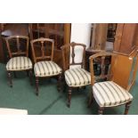 Four Edwardian walnut dining chairs, with scroll carved cresting rails and pierced splat backs, on