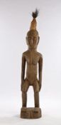 Large West African carved figure, with high hair above the elongated face, hands to the waist and
