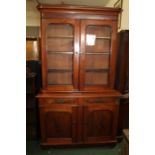 Victorian mahogany bookcase, the down-swept pediment above two arched glazed doors revealing three
