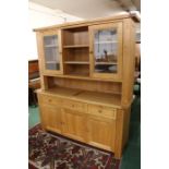 Light oak dresser, with central shelves flanked by two glazed cupboards, the base with three