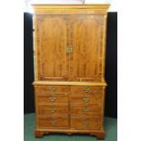 Walnut veneered cupboard, the dentil pediment above two simulated panelled cupboard doors opening to