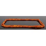 Amber necklace, with a long row of graduated beads, 153cm long, the largest bead 14mm long, total