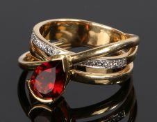 18 carat gold garnet and diamond set ring, with a cross over shank set with a pear cut garnet and
